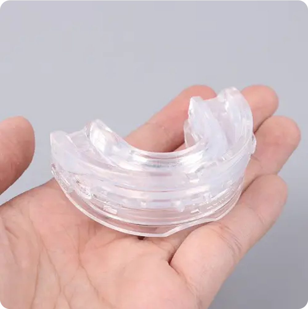 Hand holding a clear dental mouthguard.