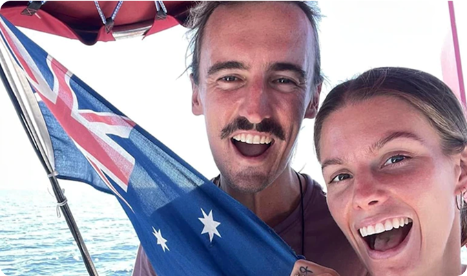 Two people smiling with an Australian flag on a boat.