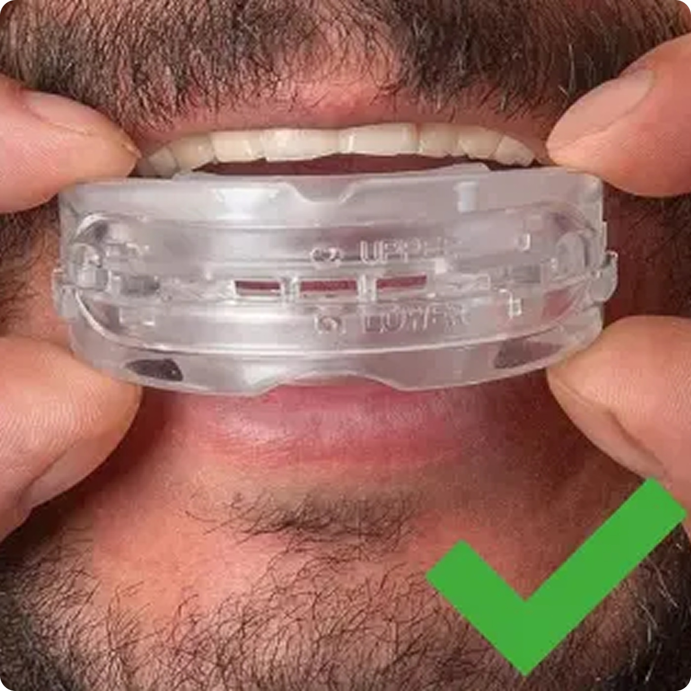 Person holding a clear dental mouthguard with a green checkmark.