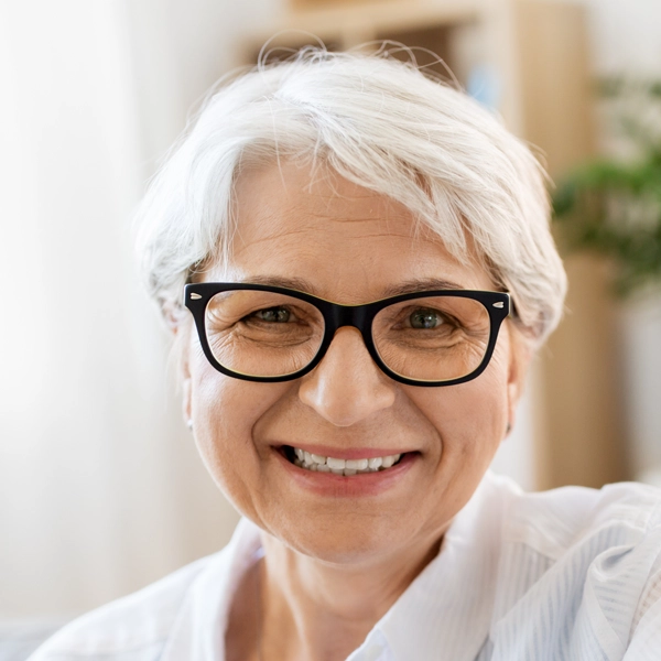 Smiling person with short white hair and glasses.