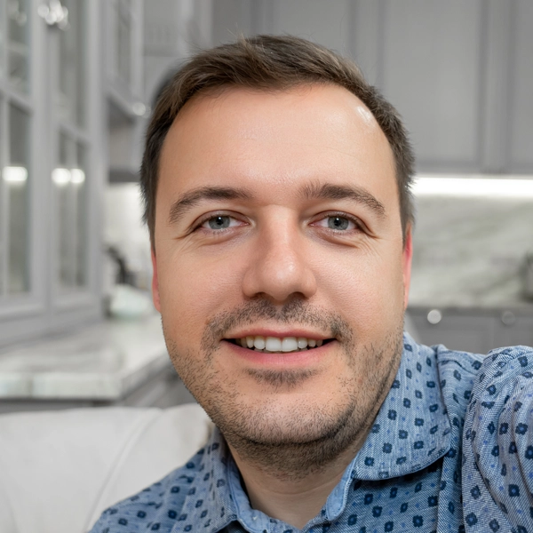 Smiling man taking a selfie in a modern kitchen.