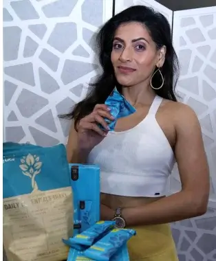 Person holding a blue snack package, standing by a table with more packages.