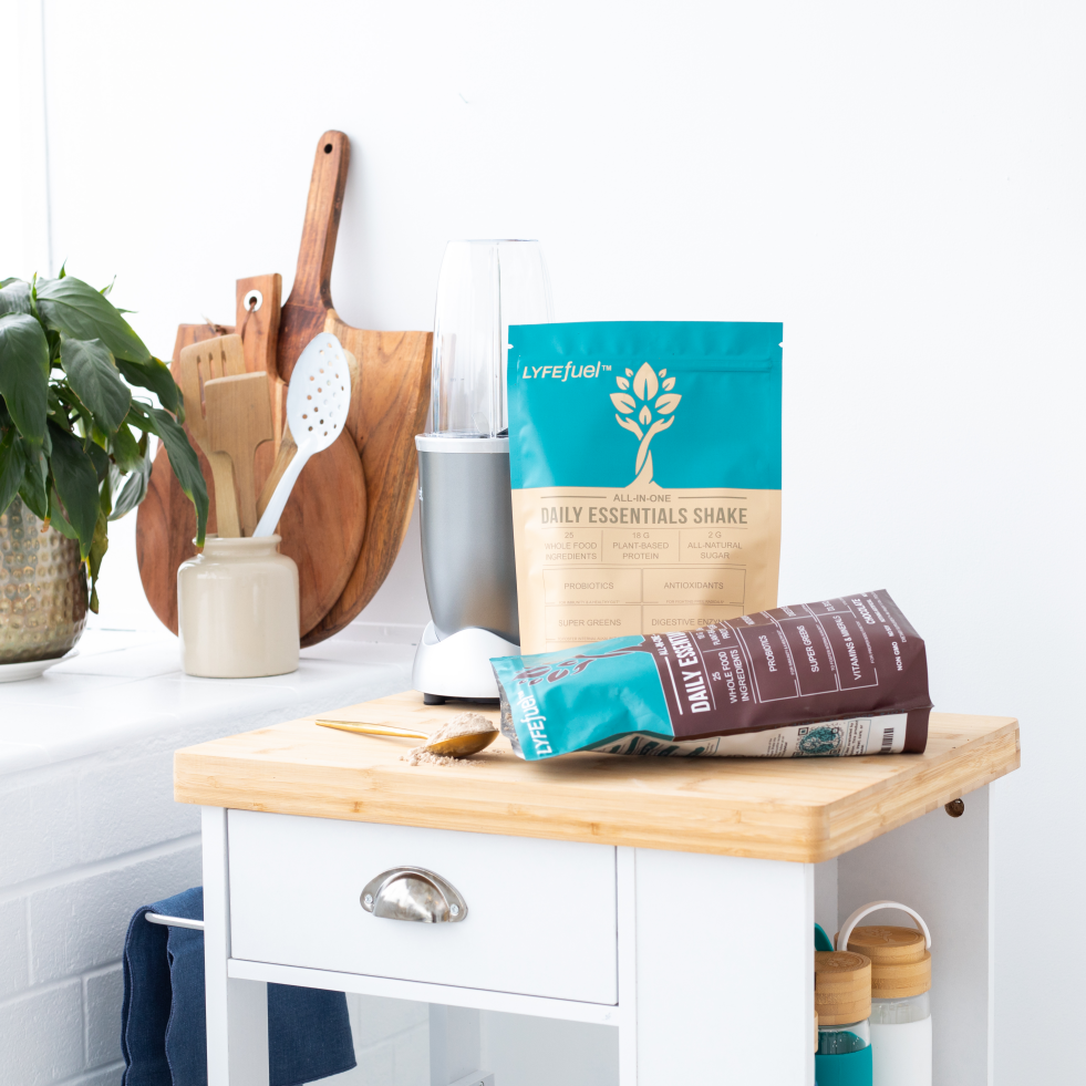 Kitchen counter with protein shake bags, blender, and wooden utensils.