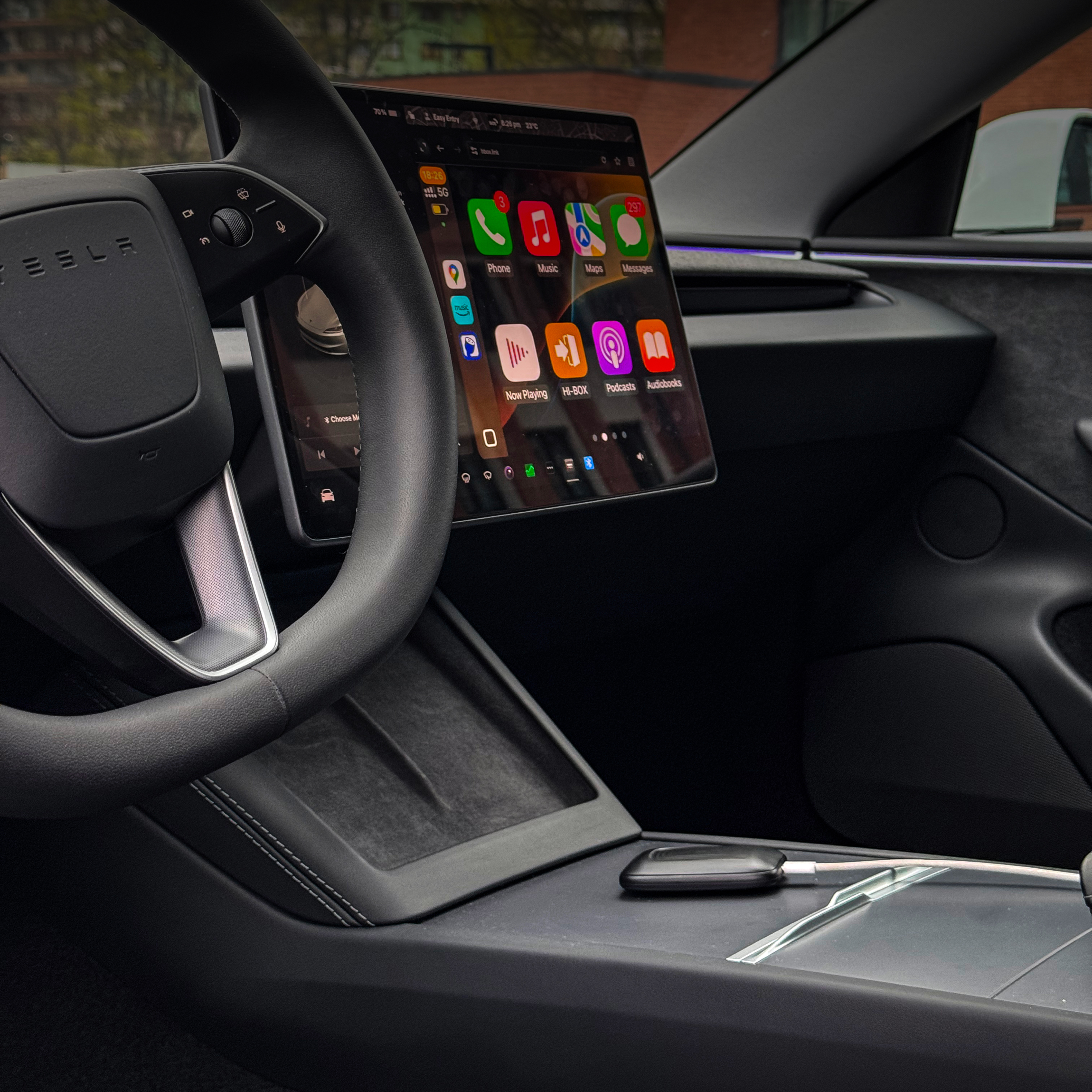Car interior showing steering wheel and touchscreen dashboard display.