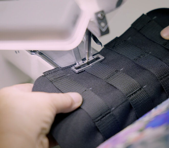 Person using a sewing machine to stitch black fabric.