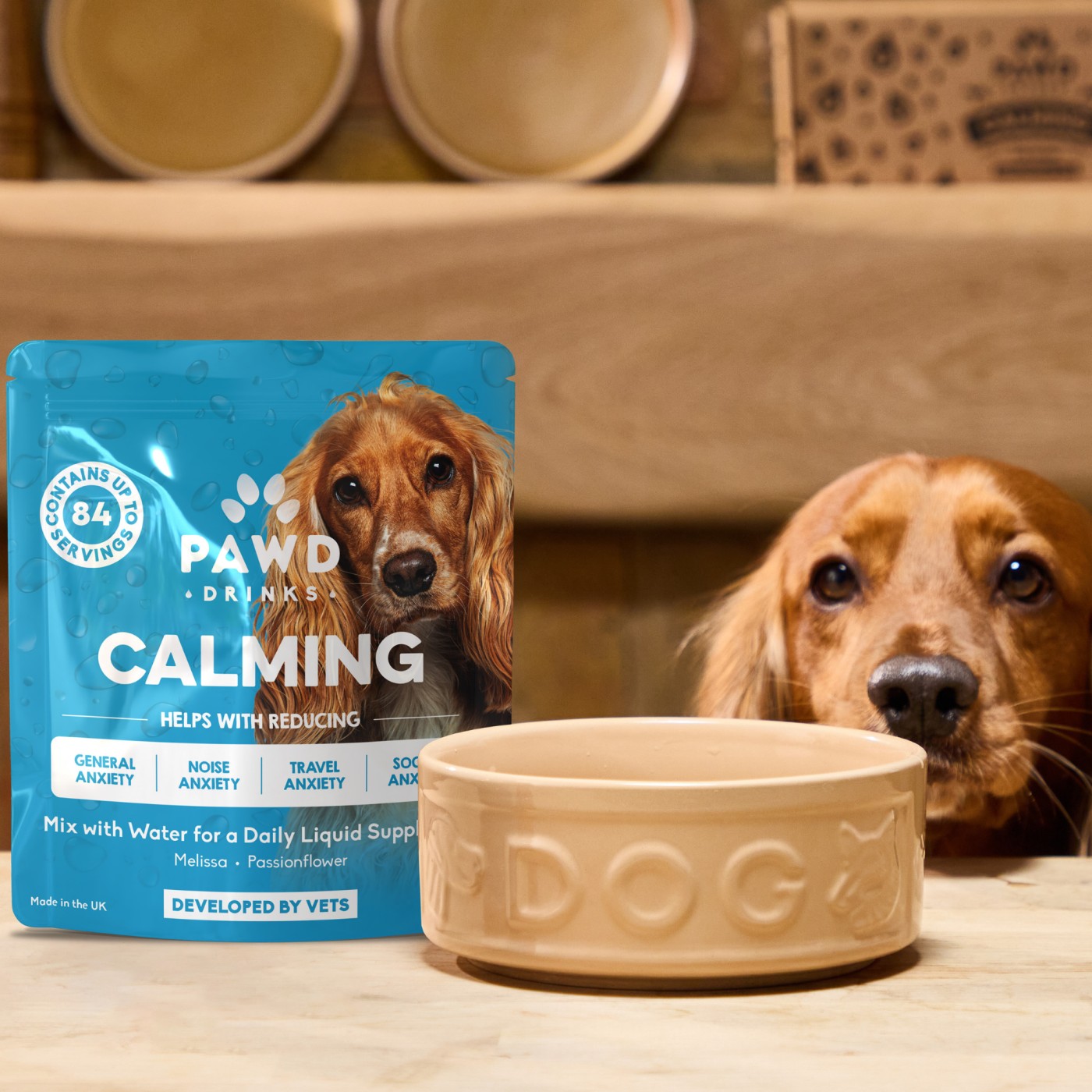 Dog with calming drink packet and dog bowl on a table.