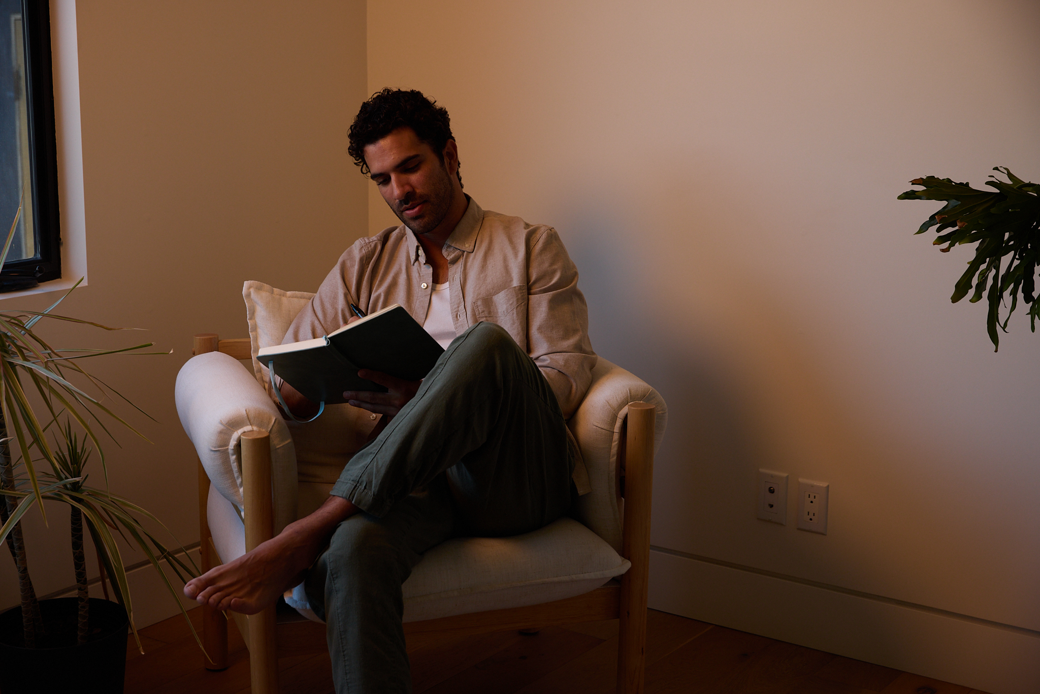 Person sitting in a chair reading a book in a cozy room.