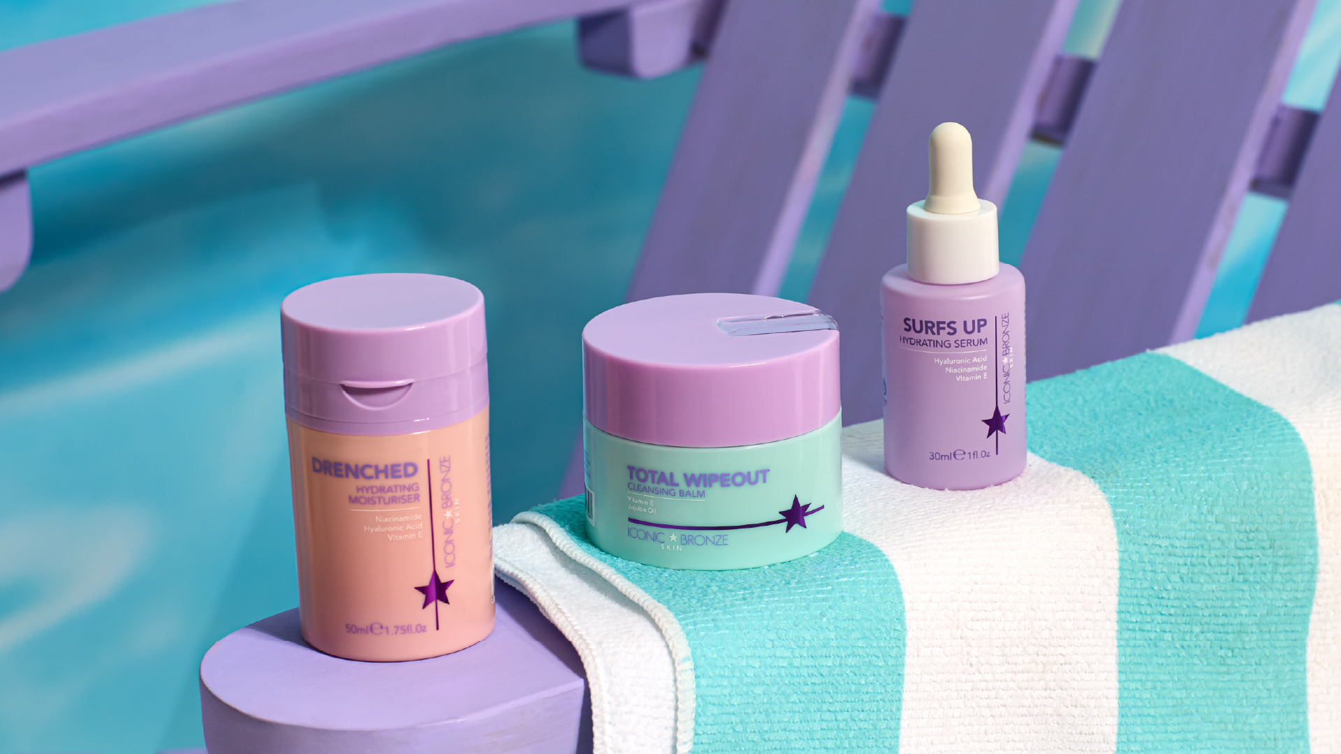 Three skincare products on a striped towel by a poolside chair.