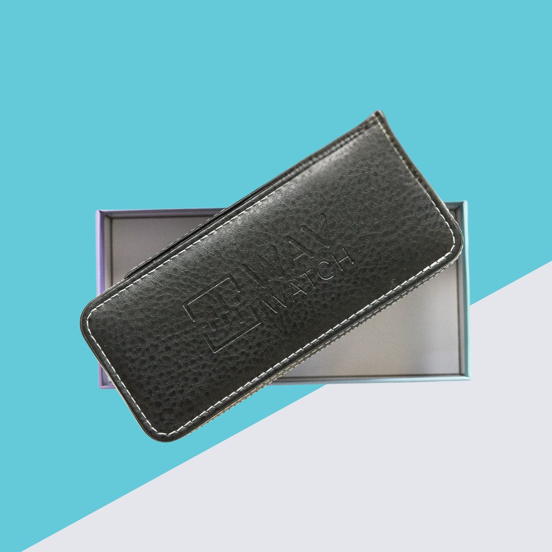 A black textured watch case with white stitching rests on an open box against a colorful background.