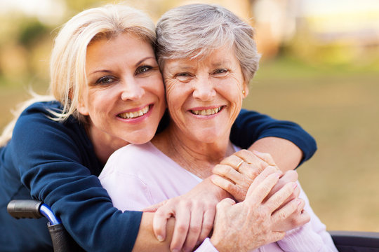 Two women smiling and embracing outdoors.