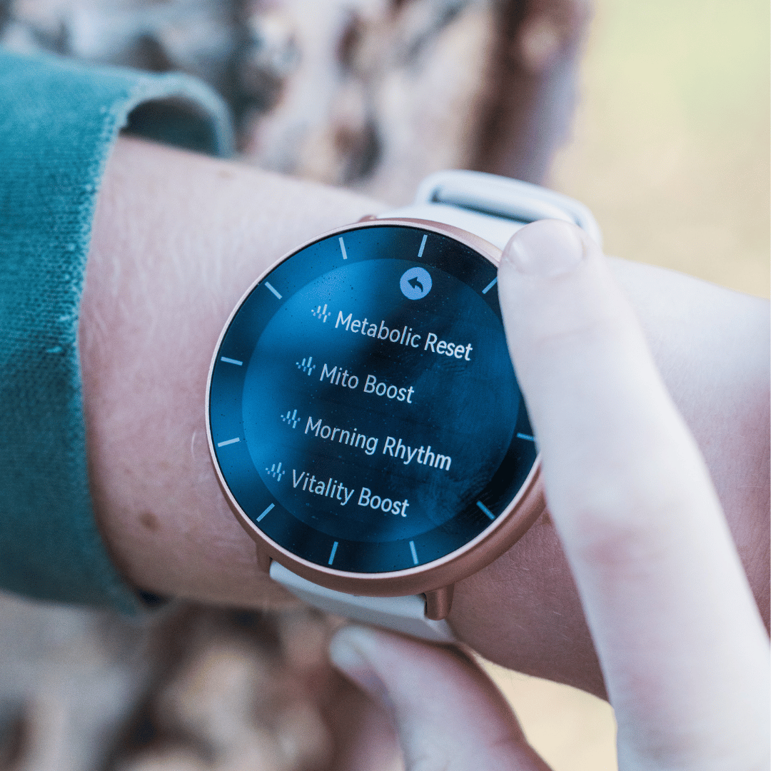 A close-up of a person's wrist with a smartwatch displaying a menu of wellness features.
