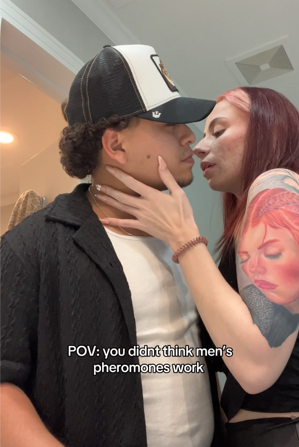 Two people standing close, one with a tattoo, in a bathroom setting.