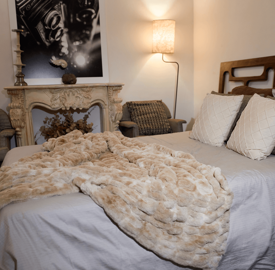 Cozy bedroom with neutral tones, plush blanket on bed, soft lighting, and a vintage camera photo.