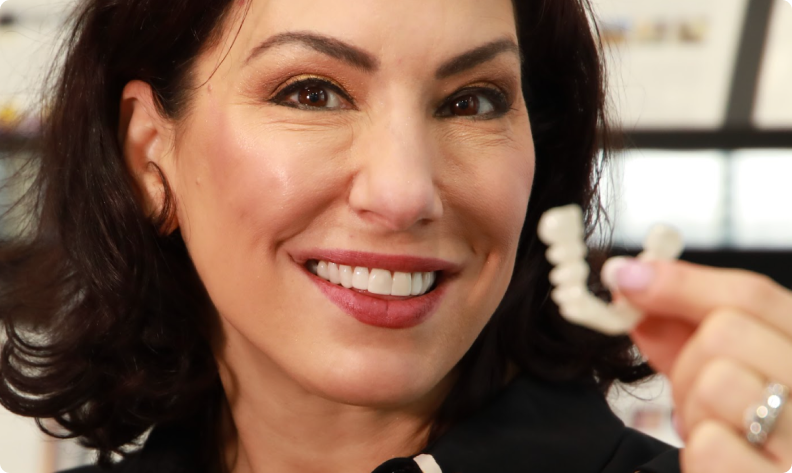 Person smiling and holding a dental aligner.