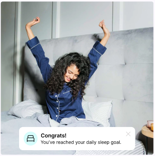 Woman stretching in bed with a notification about reaching sleep goal.