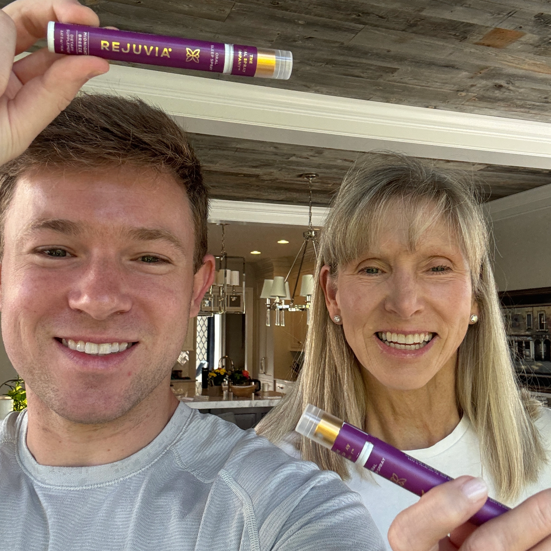 A man and a woman smile while each holds up a purple tube of Rejuvia oral sleep spray.