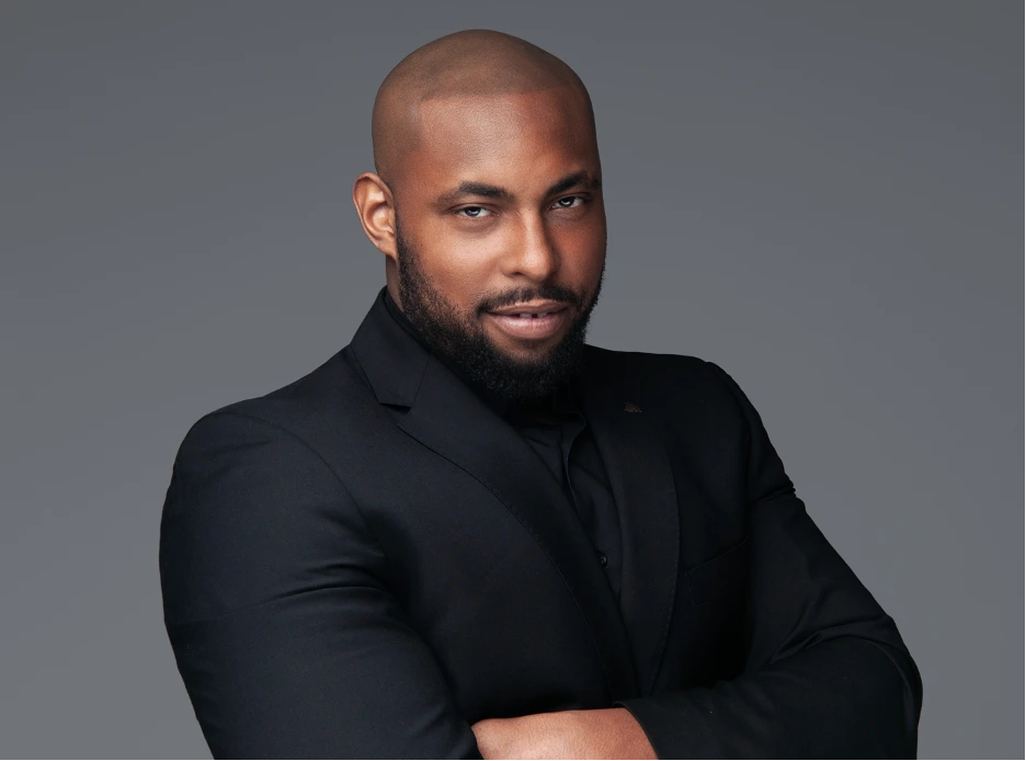 Man in a black suit with a confident expression.