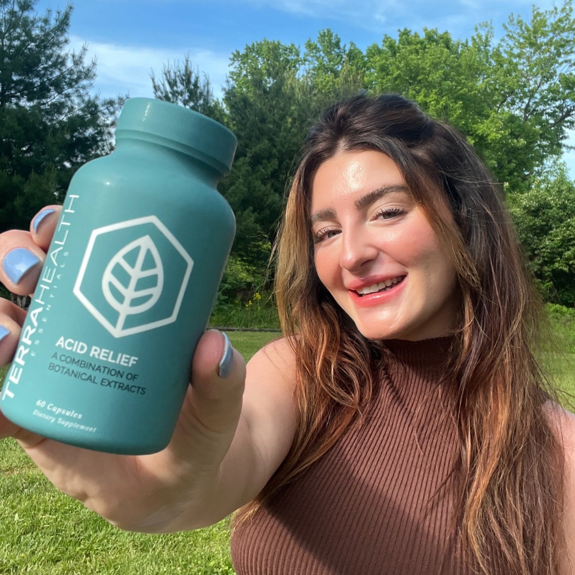 Person holding a bottle labeled 'Acid Relief' outdoors with trees in the background.