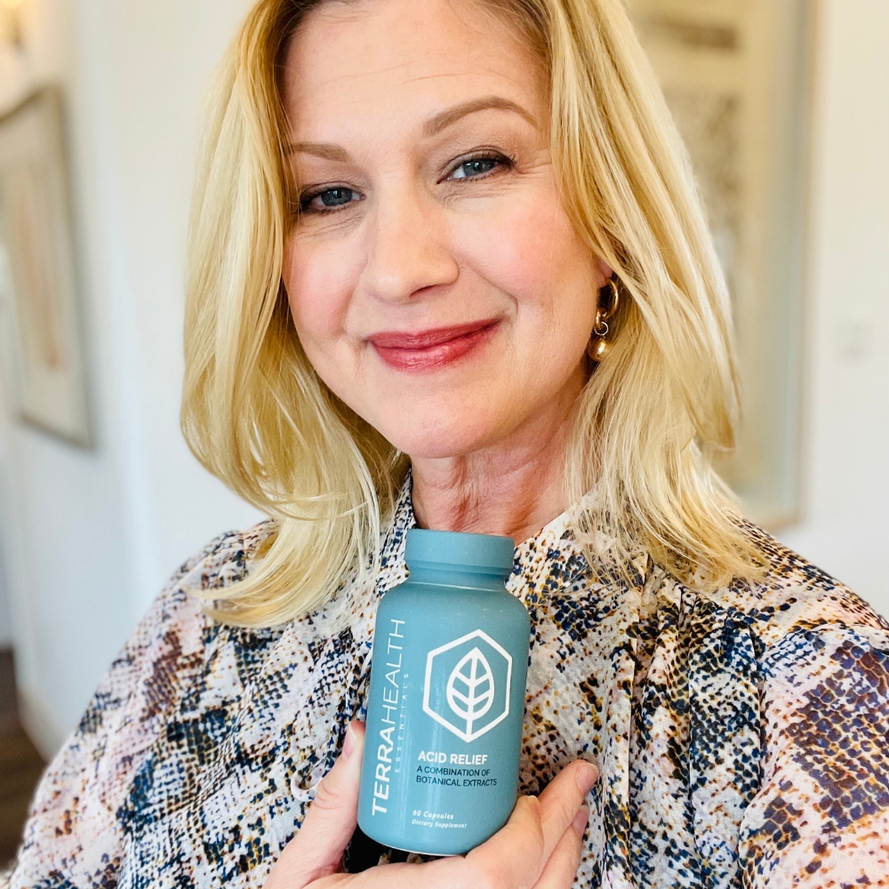 Person holding a bottle labeled 'Terra Health Acid Relief.'