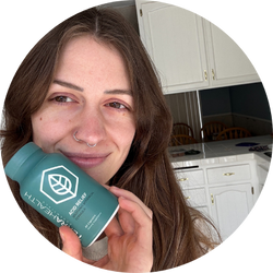 Person holding a green bottle in a kitchen setting.