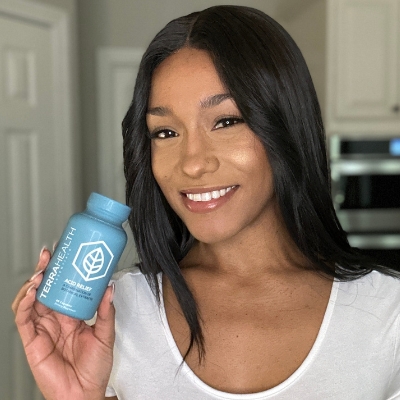 Person holding a blue bottle labeled 'Terra Health Acid Relief.'