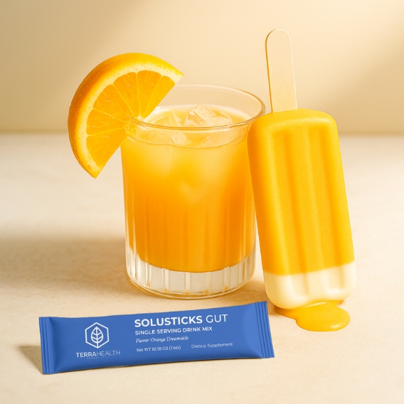 Orange drink with slice, popsicle, and blue Solusticks Gut packet.