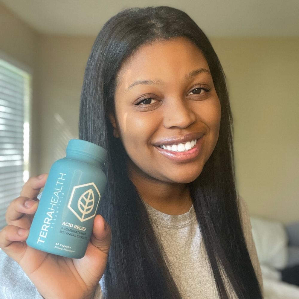 Person smiling and holding a bottle labeled 'Terra Health Acid Relief.'