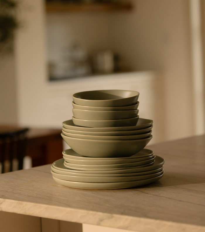 Stack of green ceramic plates and bowls on a table