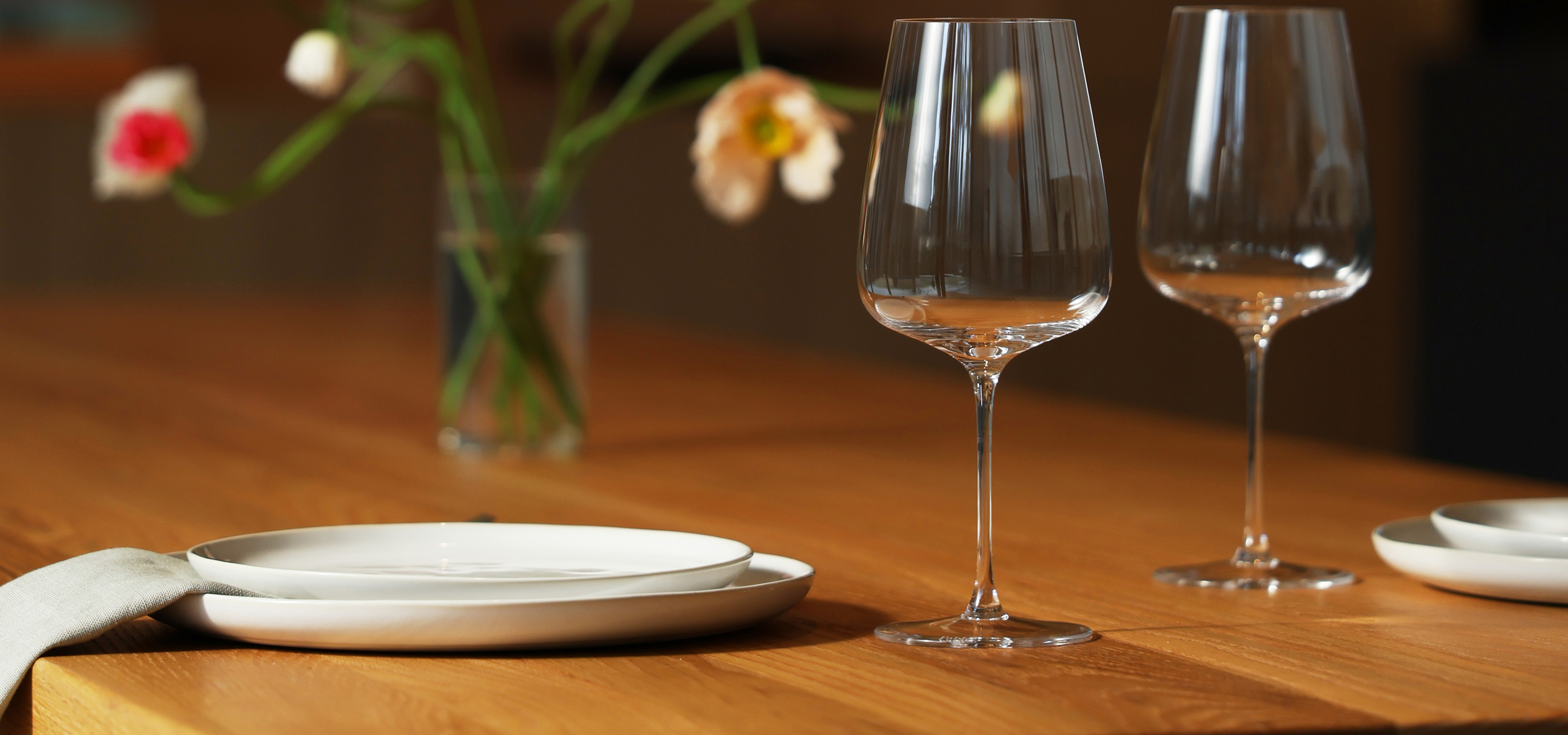Two empty wine glasses and plates on a wooden table.