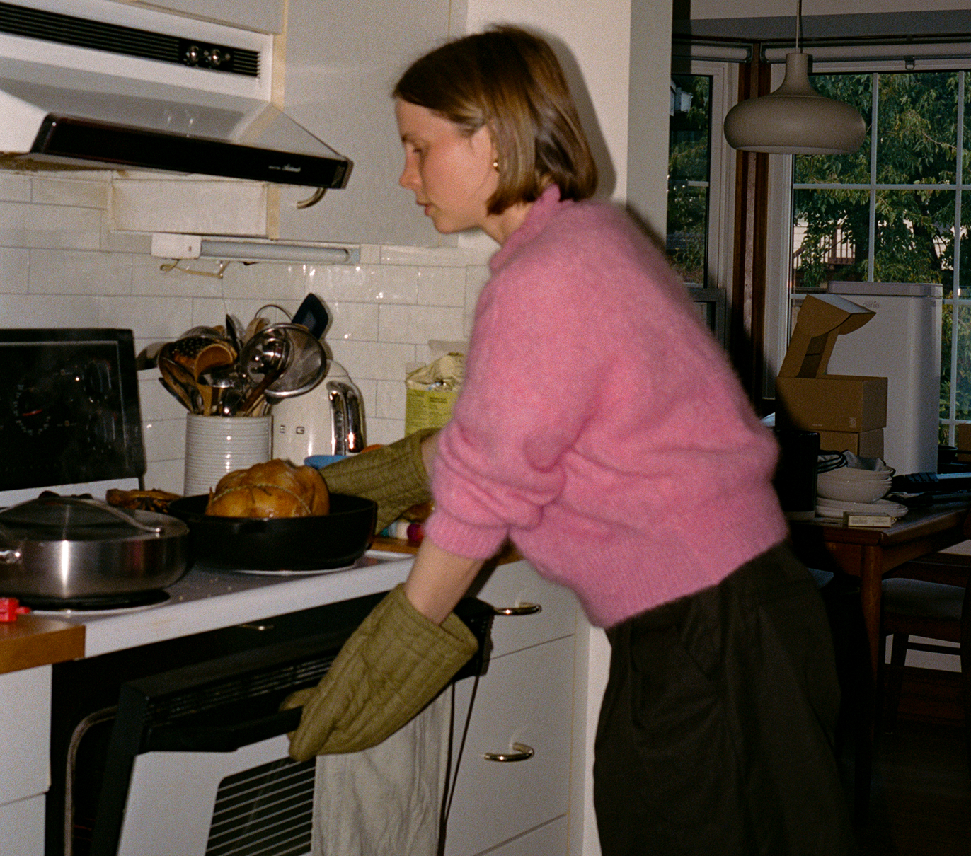 Person wearing pink sweater cooking a dish in the kitchen.