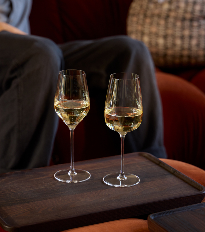 Two glasses of white wine on a wooden tray