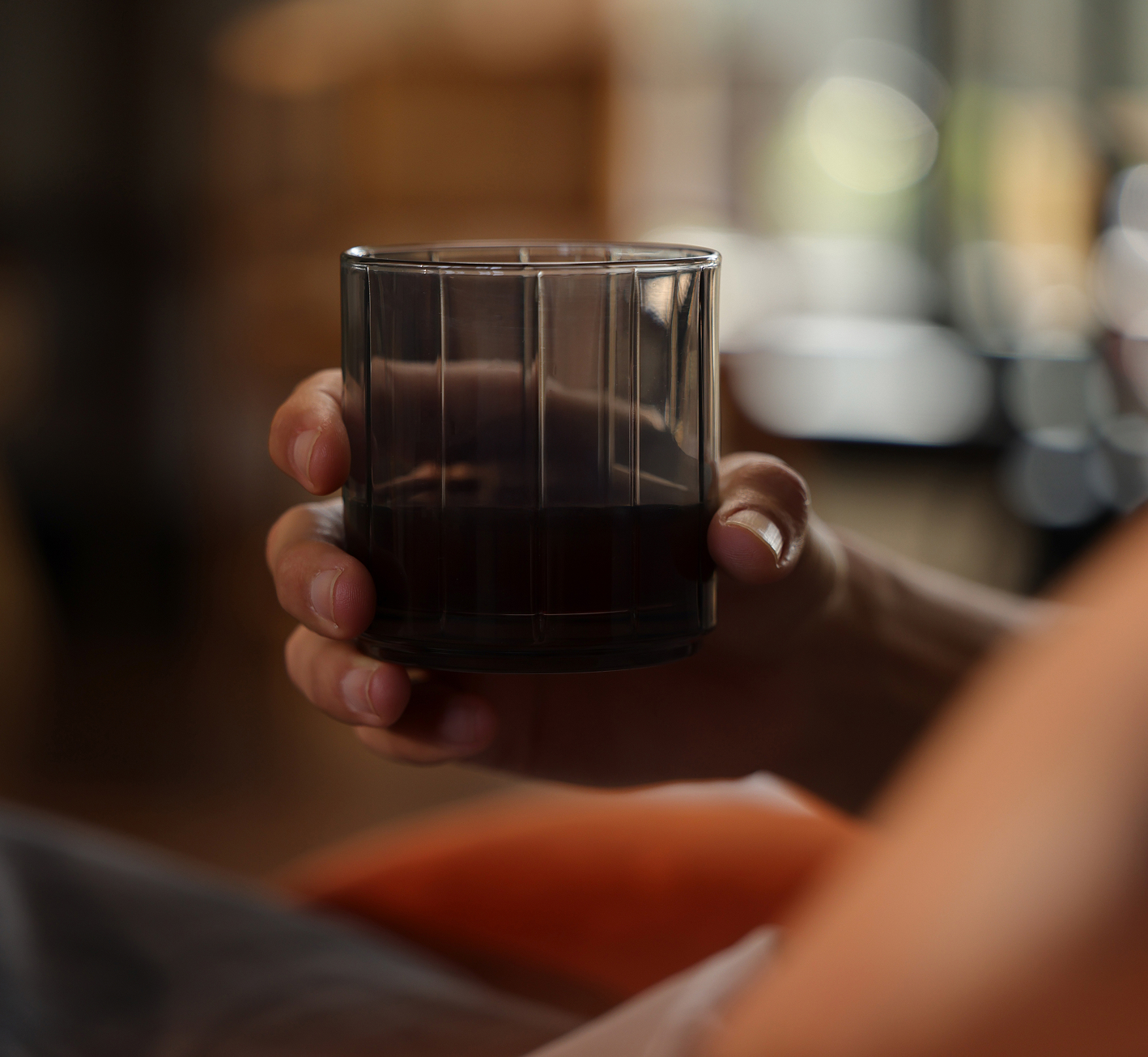 A woman is holding a glass with a drink in her hand
