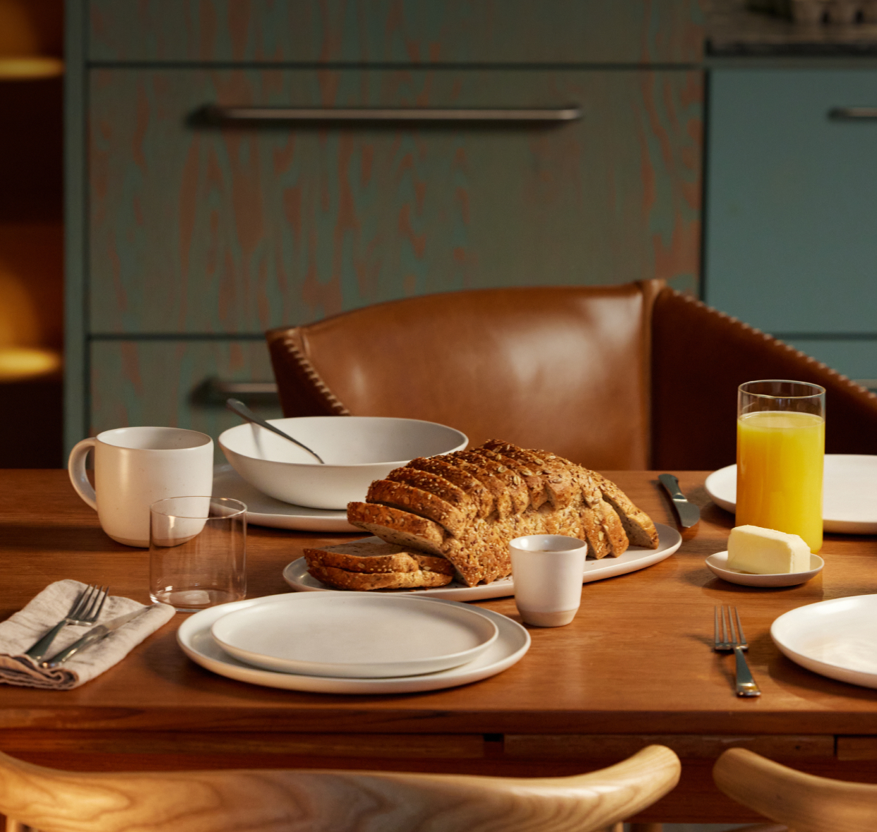 Breakfast table with sliced bread, orange juice, and butter.