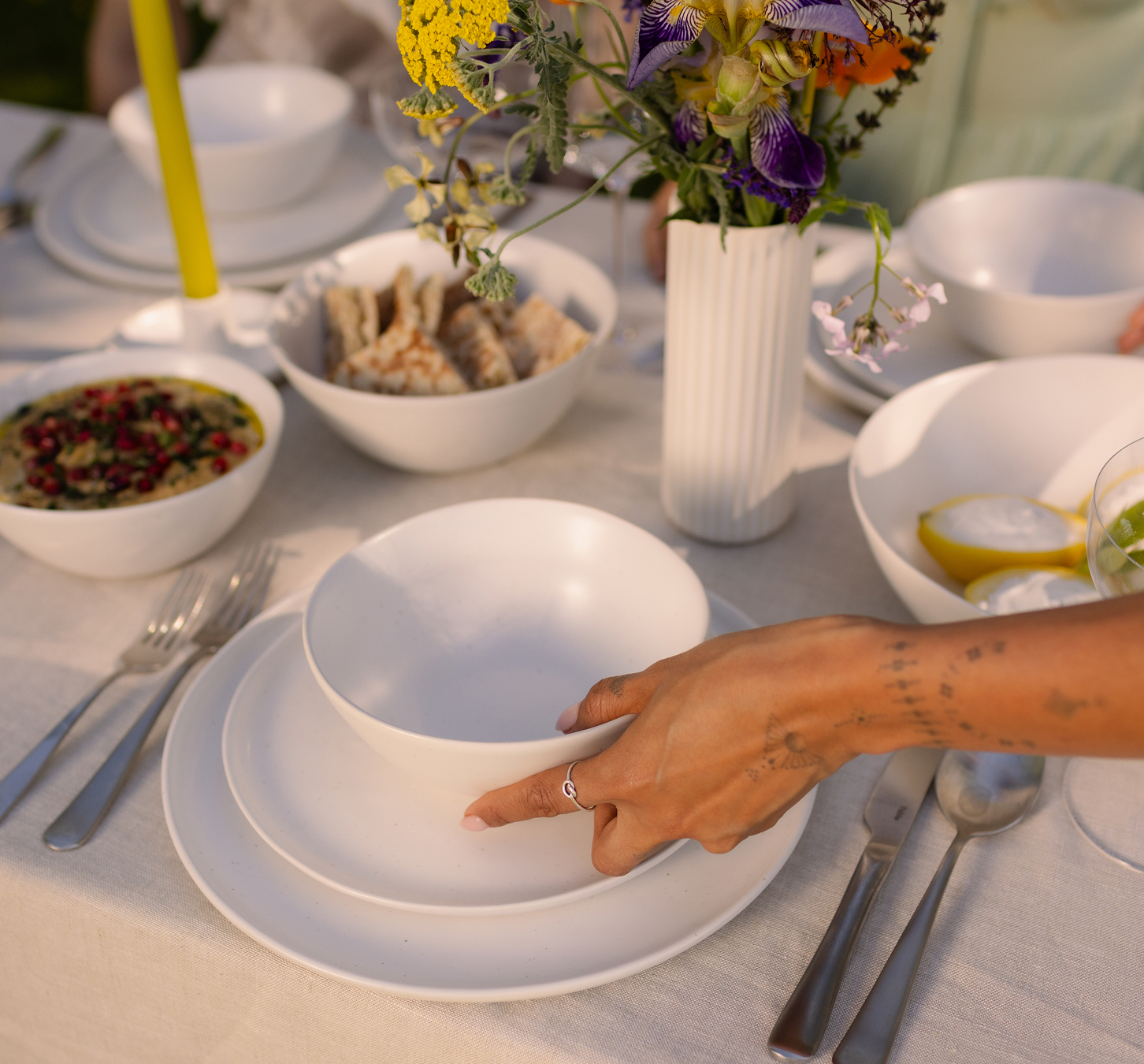 A woman sets the table with white tableware