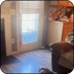 A cozy living room with a couch, wooden floor, and sunlight through a glass door.