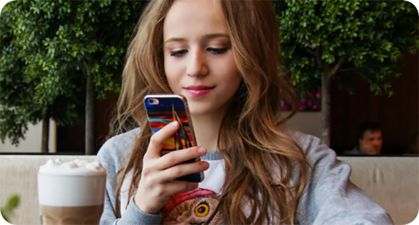Person looking at a smartphone with a coffee on the table.