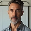Portrait of a man with gray hair and beard, wearing a collared shirt.