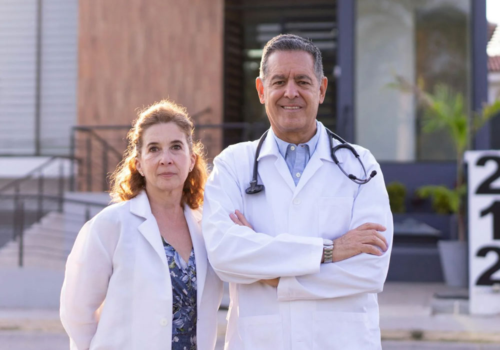 Two doctors in white coats standing outside a building.