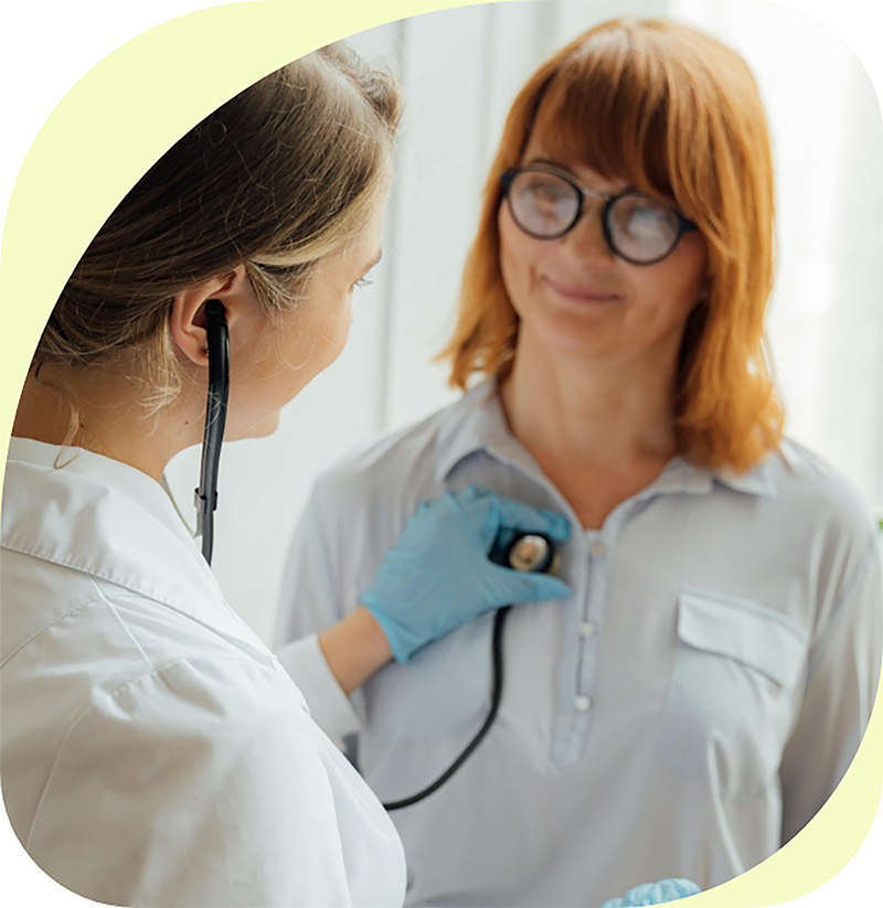 Doctor using stethoscope on a smiling patient in a medical setting.