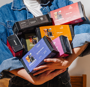 Person holding multiple colorful coffee product boxes.