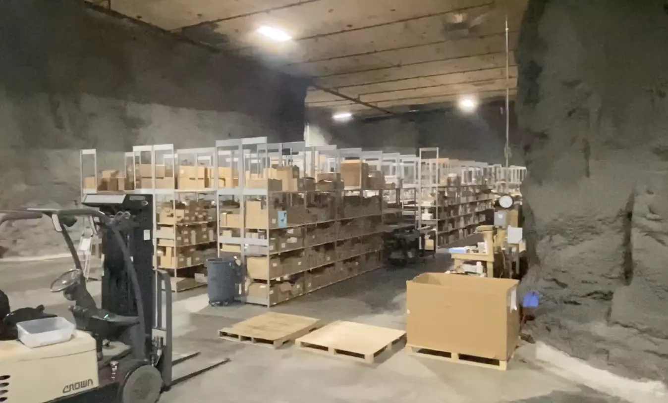 Underground storage area with shelves of boxes and a forklift.
