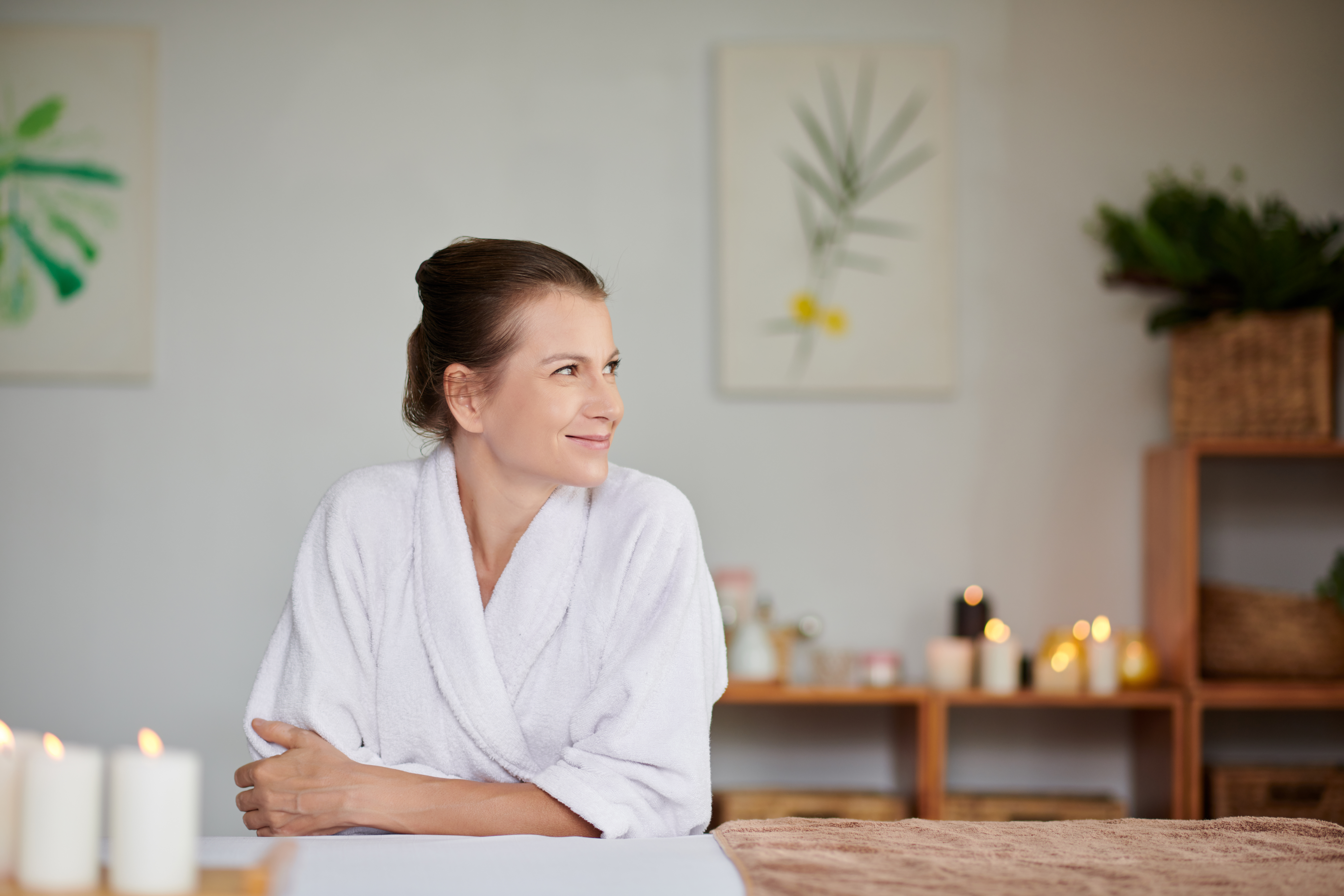 Person in a robe using a handheld device on their leg near a bathtub.