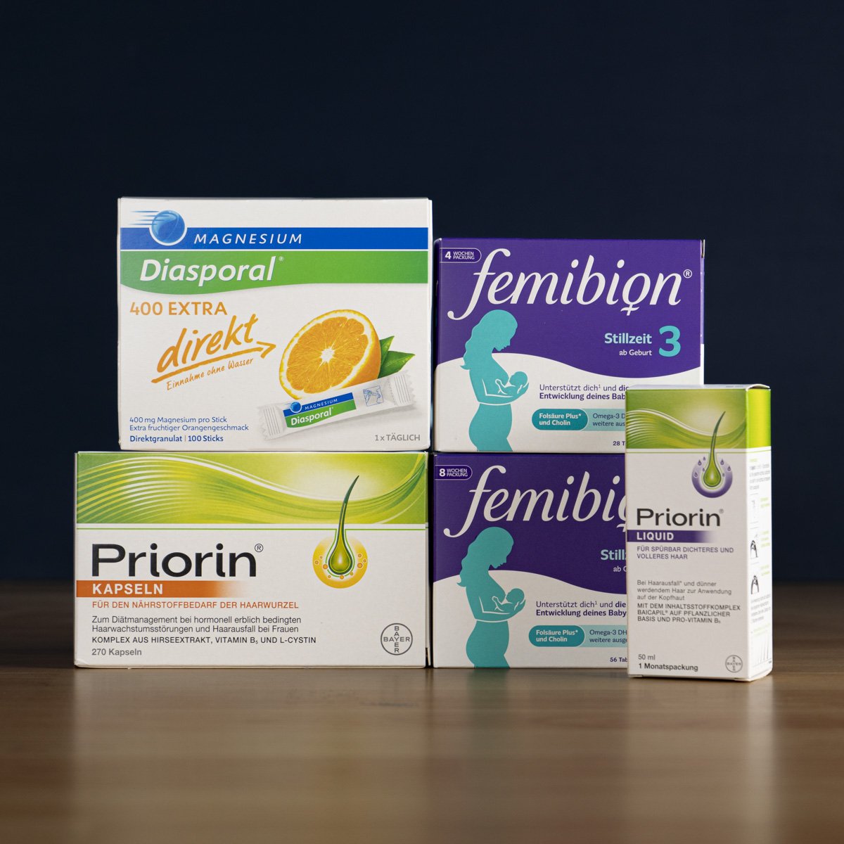 Several boxes of German supplements, including Diasporal, Femibion, and Priorin, are stacked against a dark background.