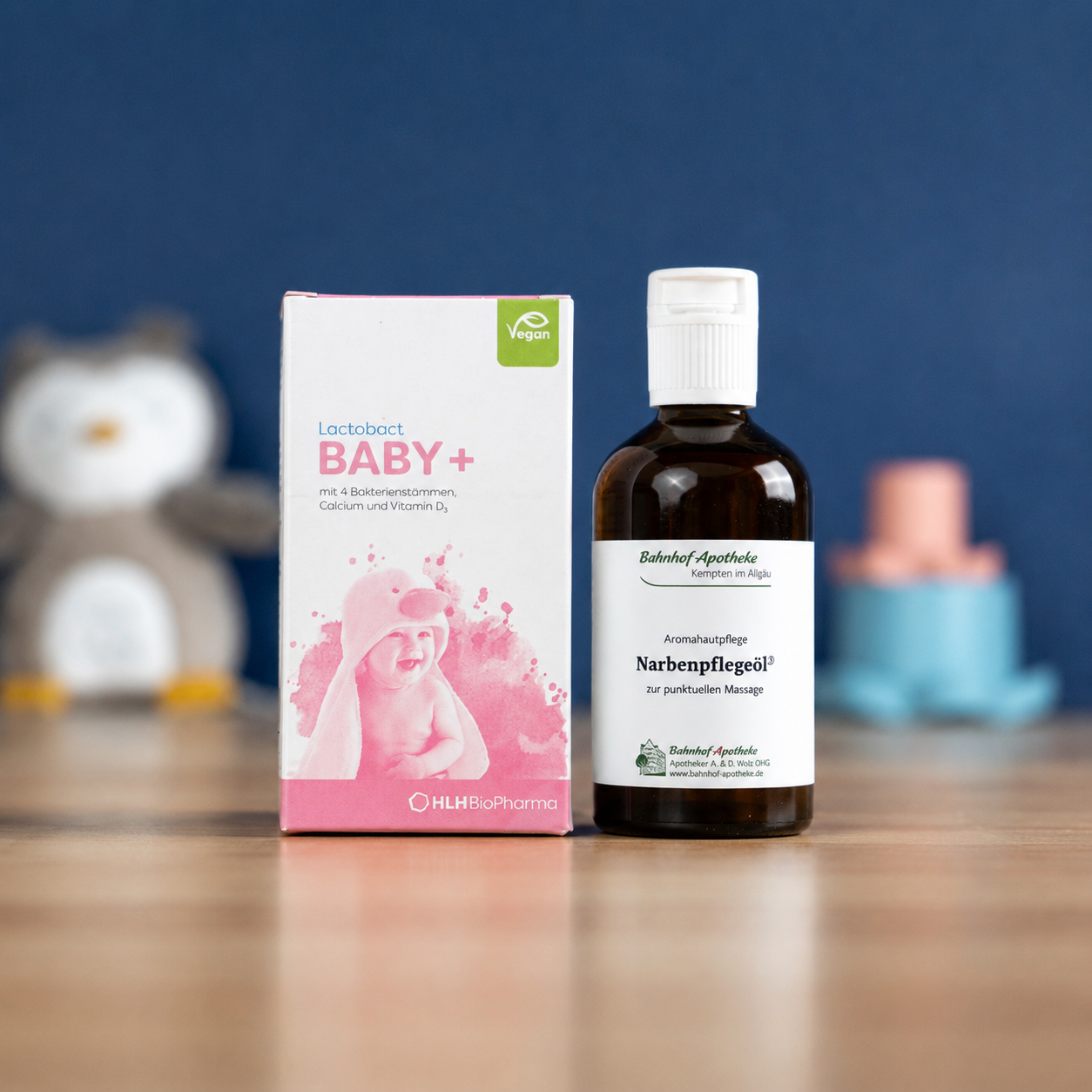 A box of Lactobact BABY+ supplements and two bottles of Bahnhof Apotheke oils on a wooden table.