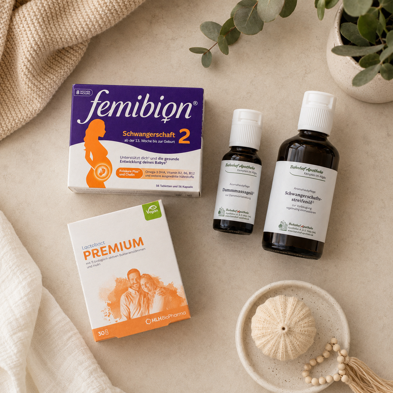 A flat lay of various pregnancy supplements and body oils on a neutral surface with decorative items.
