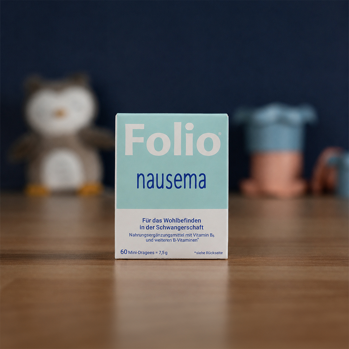 A box of Folio nausema sits on a wooden surface, with a blurred stuffed owl in the background.