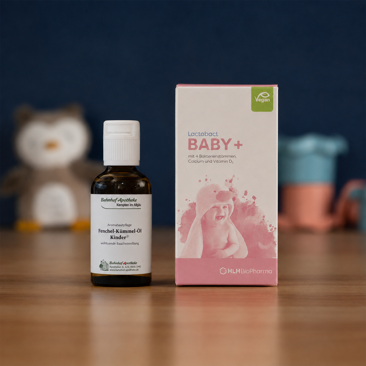 A bottle of Fenchel-Kümmel-Öl and a box of Lactobact BABY+ sit on a wooden table.
