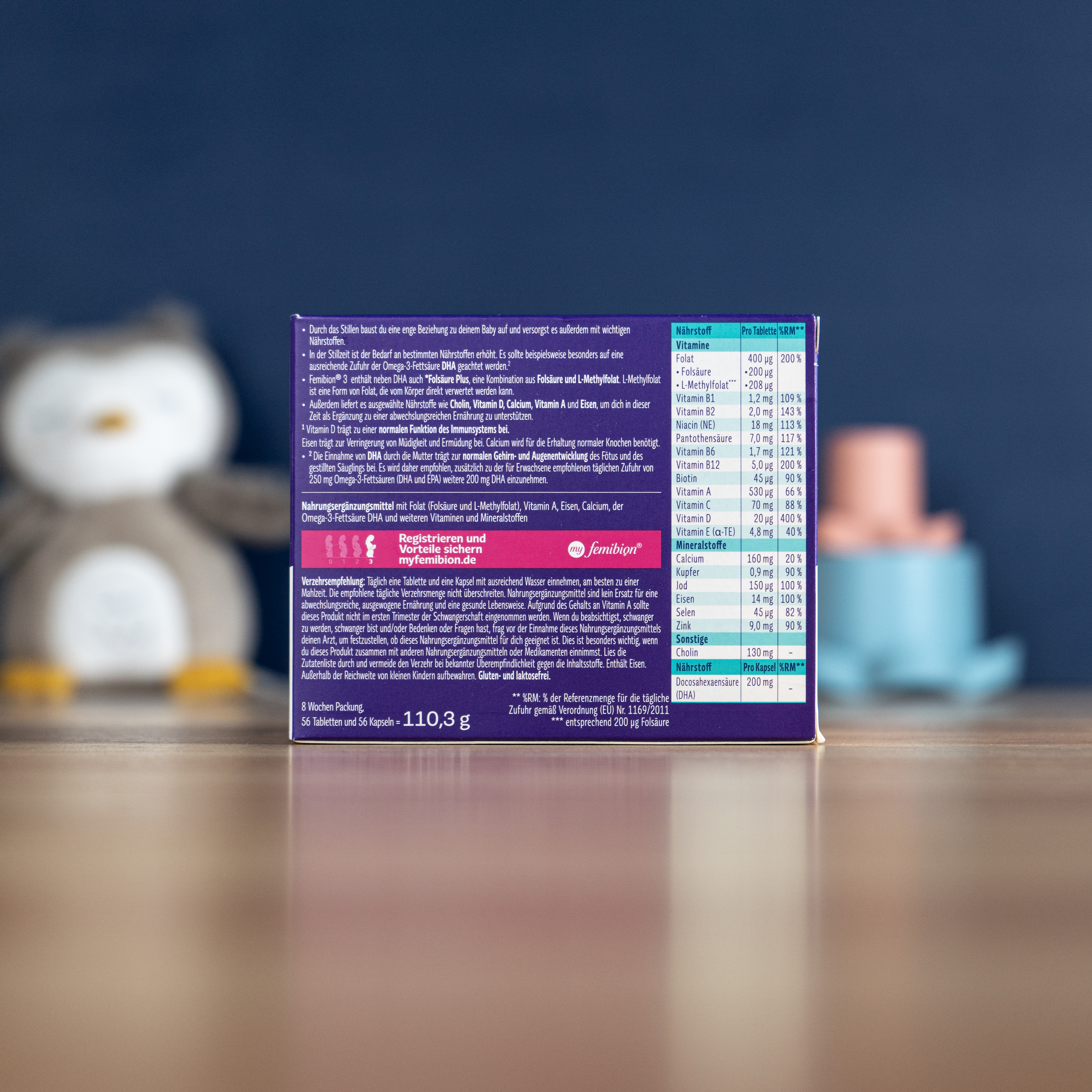 Boxes of Femibion and Folio nausema pregnancy supplements stacked on a wooden counter in a pharmacy.