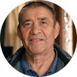 A smiling older man in a casual shirt, indoors.