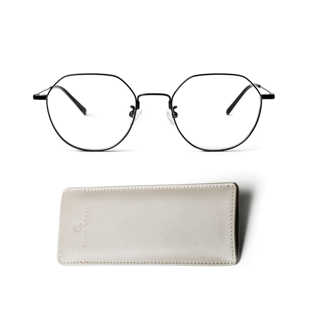 A pair of black, thin-framed geometric eyeglasses sits above a light gray leather case on a white background.